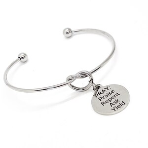 Può includere: Braccialetto rigido in argento con un ciondolo annodato che dice "PRAY: Praise Repent Ask Yield".