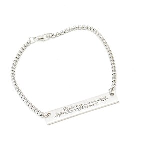 May include: A silver bracelet with a rectangular charm that reads "Raising Arrows Psalm 127:4".