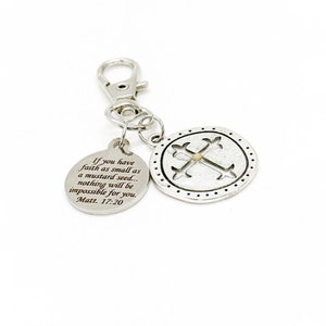 Op de afbeelding: Zilveren sleutelhanger met een ronde hanger met een kruis en de tekst "Als je geloof hebt, zo klein als een mosterdzaad... niets zal voor jou onmogelijk zijn. Mattheüs 17:20".