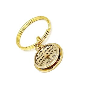 May include: A gold-colored keychain with a circular pendant. The pendant contains text on a cream-colored background. The text reads "You have faith as small as a mustard seed, nothing will be impossible for".