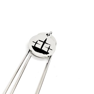 May include: Silver bookmark with a black silhouette of a church on a round charm.