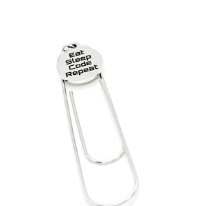 May include: Silver bookmark with a round charm that says "Eat Sleep Code Repeat".