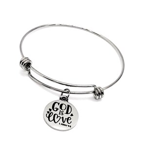 May include: A silver expandable bangle bracelet with a round charm that says "God is love" with a heart symbol and "1 John 4:8" underneath.