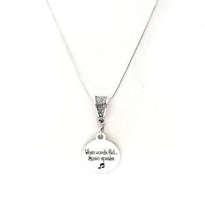 May include: Silver necklace with a round pendant that says "When words fail, Music speaks" with a musical note symbol.