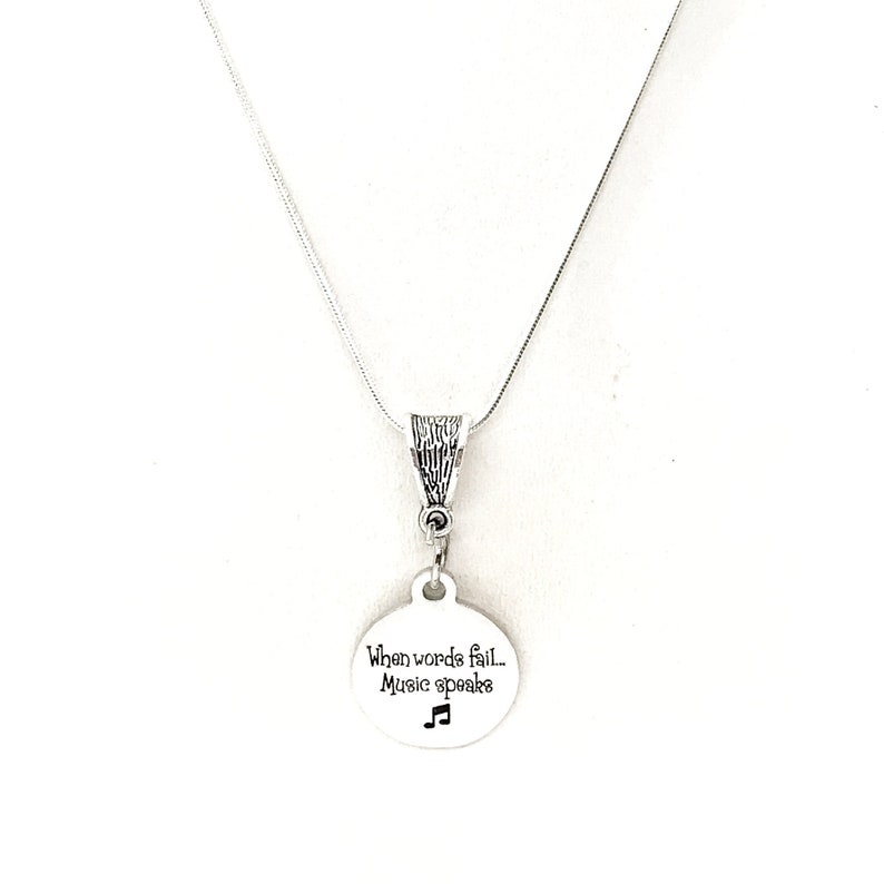 May include: Silver necklace with a round pendant that says "When words fail, Music speaks" with a musical note symbol.