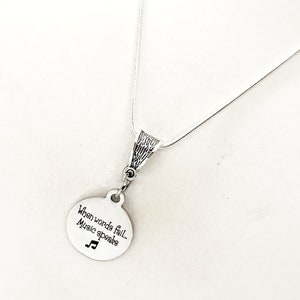 May include: A silver necklace with a round pendant that says "When words fail, music speaks" and a musical note symbol.
