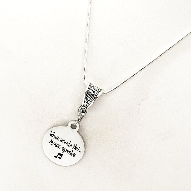 May include: A silver necklace with a round pendant that says "When words fail, music speaks" and a musical note symbol.