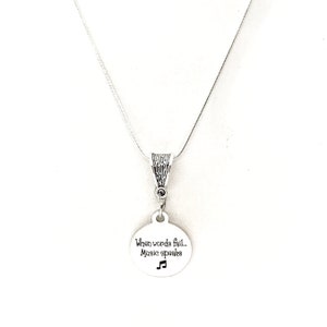 May include: Silver necklace with a round pendant that says "When words fail... Music speaks" with a musical note symbol.
