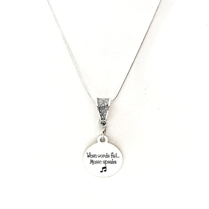 May include: Silver necklace with a round pendant that says "When words fail... Music speaks" with a musical note symbol.