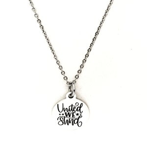 May include: A silver chain necklace with a round pendant that says "United We Stand" in black lettering.