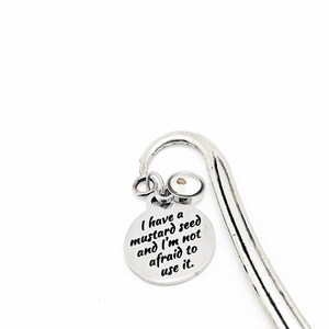 May include: Silver bookmark with a small round charm that says "I have a mustard seed and I'm not afraid to use it." The charm has a small mustard seed inside.