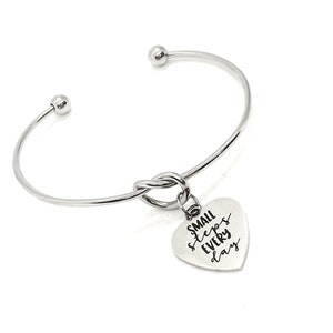May include: A silver bangle bracelet with a knotted design and a heart-shaped charm that reads "SMALL steps EVERY day".