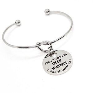 May include: Silver bangle bracelet with a knotted charm that reads "Even through deep waters I will be with you".