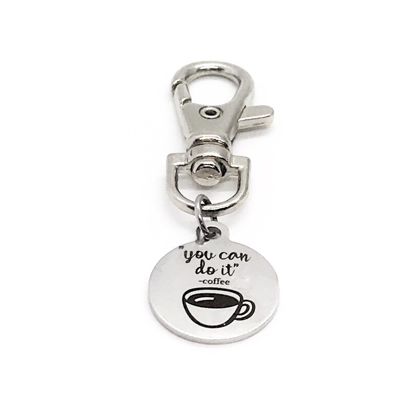 May include: Silver keyring with a round charm that says "you can do it" -coffee and has a picture of a coffee cup.