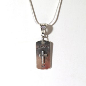 May include: Silver necklace with a silver pendant that says "Protect Me" and has a cross on it.
