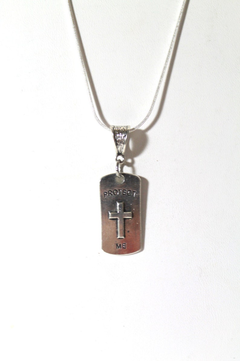 May include: Silver necklace with a silver pendant that says "Protect Me" and has a cross on it.