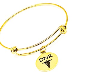 May include: A gold bangle bracelet with a round charm that says "DNR" with a medical symbol.