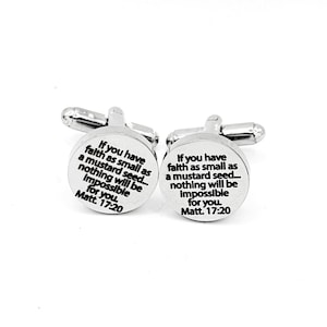 May include: A pair of silver cufflinks with a circular design. Each cufflink features the text "If you have faith as small as a mustard seed... nothing will be impossible for you. Matt. 17:20" in black font.