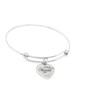 May include: A silver bangle bracelet featuring a heart-shaped charm. The charm is engraved with the words "Mama Mermaid" in cursive script and small decorative elements. The bracelet is adjustable and has a simple, elegant design.