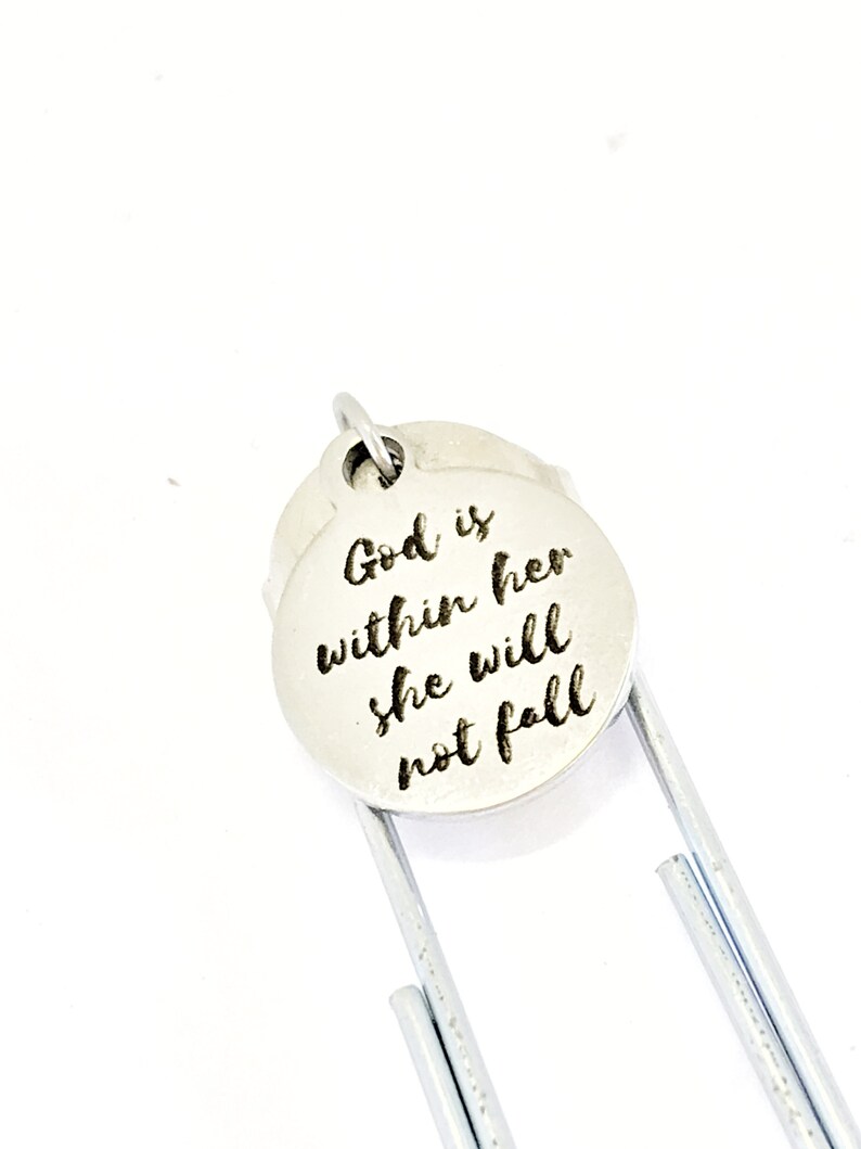 May include: Silver bookmark with a round charm that reads "God is within her she will not fall".