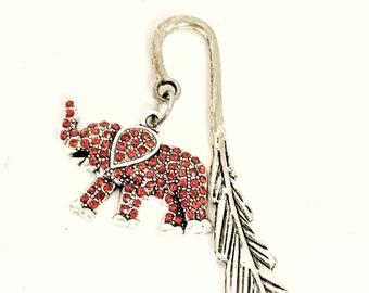 May include: Silver bookmark featuring a red jeweled elephant charm and a feather design.