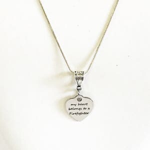 May include: Silver necklace with a heart-shaped pendant that reads "my heart belongs to a Firefighter".