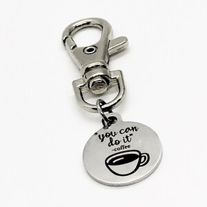 May include: Silver keyring with a round charm that says "You can do it - coffee" with a small coffee cup graphic.