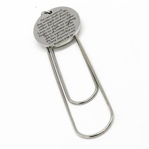 May include: A silver bookmark with a round metal charm featuring a bible verse: "For I am convinced that neither death nor life, neither angels nor demons, neither the present nor the future, nor any powers, neither height nor depth, nor anything else in all creation, will be able to separate us from the love of God that is in Christ Jesus our Lord. Romans 8:38-39"