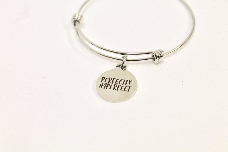 Peut inclure: Un bracelet jonc argent&eacute; avec un charme rond qui dit "Perfectly Imperfect".