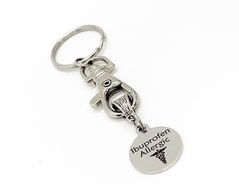 May include: Silver keychain with a silver clasp and a round tag that says "Ibuprofen Allergic" with a medical symbol.