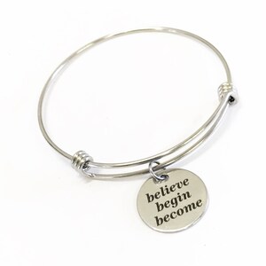 May include: Silver bangle bracelet with a round charm that says "believe begin become".