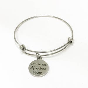 May include: Silver expandable bangle bracelet with a charm that reads "And so the adventure begins".
