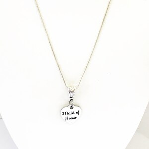 Puede incluir: Un collar de plata con un colgante en forma de coraz&oacute;n que dice "Maid of Honor".