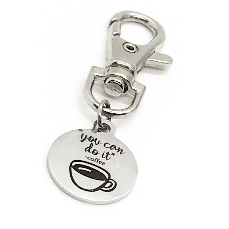 May include: Silver keyring with a round charm that says "you can do it" with a coffee cup icon and the text "coffee" underneath.