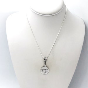 May include: Silver necklace with a round pendant that reads "When words fail, music speaks".