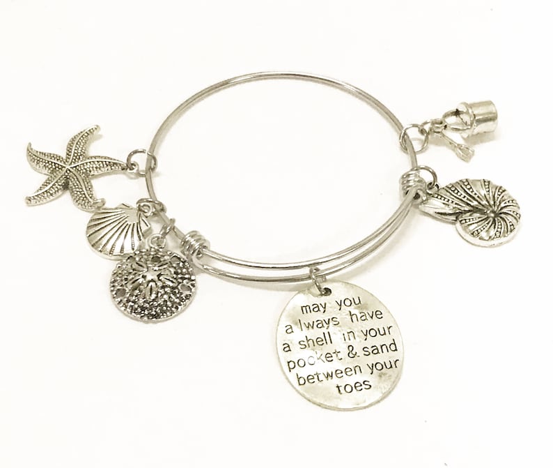 Może przedstawiać: Srebrna bransoletka z zawieszką w kształcie muszli, gwiazdą morską i zawieszką z tekstem "may you always have a shell in your pocket & sand between your toes".