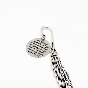 May include: A silver-colored bookmark with a feather design and a circular charm. The charm has engraved text that reads "God, I surrender... Please give me strength to move forward."