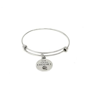 Puede incluir: Pulsera de brazalete de plata con un dije que dice "Comer Dormir Tejer" y un pequeño icono de ovillo de lana.