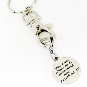 May include: Silver keychain with a round charm that reads "For I am about to do something new. Isaiah 43:19"