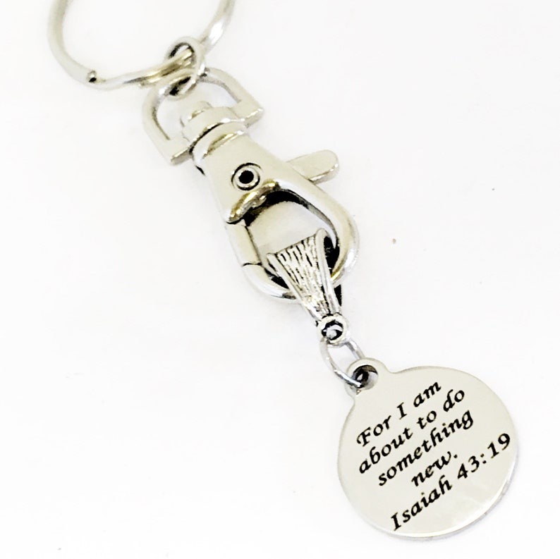 May include: Silver keychain with a round charm that reads "For I am about to do something new. Isaiah 43:19"