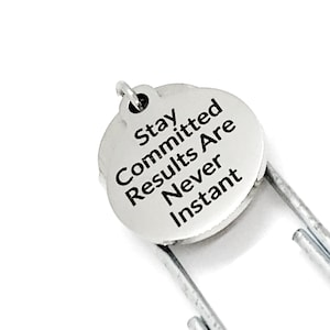 May include: Silver bookmark with a round charm that says "Stay Committed Results Are Never Instant".