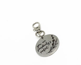May include: Silver keychain with a round charm that says "You are somebody's perfect" with a floral design.