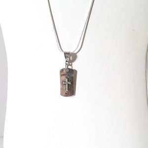 May include: Silver necklace with a silver pendant that says "Protect Me" and has a cross on it.
