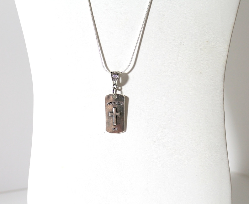 May include: Silver necklace with a silver pendant that says "Protect Me" and has a cross on it.