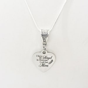 May include: Silver necklace with a heart-shaped pendant that reads "I have an Angel in Heaven, I call her Mom". The pendant has a small feather design.