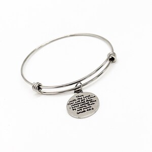 Pode incluir: Um bracelete de prata com um amuleto que diz "Assim diz o Senhor... Não temas, porque eu te remi, te chamei pelo teu nome, tu és meu. Isaías 43:1".