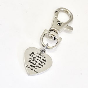Peut inclure: Porte-clés en forme de cœur argenté avec un fermoir argenté. Le cœur porte une inscription qui dit "Fais confiance au Seigneur de tout ton cœur... et il dirigera tes pas. Proverbes 3:5,6"