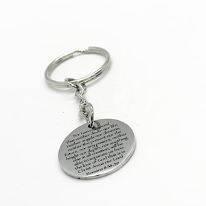 May include: Silver keychain with a round charm featuring a bible verse from Romans 8:38-39. The verse reads: "For I am convinced that neither death nor life, neither angels nor demons, neither the present nor the future, nor any powers, neither height nor depth, nor anything else in all creation, will be able to separate us from the love of God that is in Christ Jesus our Lord. Romans 8:38-39"