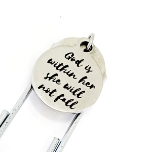 May include: Silver bookmark with a round charm that reads "God is within her she will not fall".