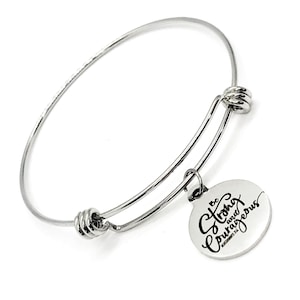 May include: Silver expandable bangle bracelet with a round charm that says "Be strong and courageous" with a Bible verse reference.